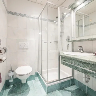 Modernes Badezimmer mit grüner Marmorplatte, Duschkabine und weißen Fliesenwänden